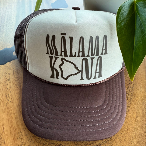 A brown and beige trucker hat that say Malama Kona on the front